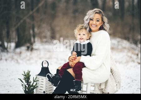 Una giovane madre seduta su una sedia all'aperto con lei figlio in grembo Foto Stock