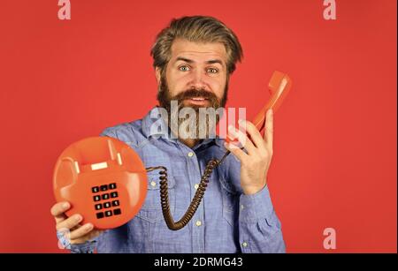 Vieni a trovarci. Tecnologia vintage nella vita moderna. Giovane uomo che parla al telefono. Anziano hippster che mostra il vecchio telefono. Brutale ragazzo con telefono. adulto barbuto uomo parlare su retro telefono. Foto Stock