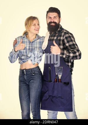 Attrezzi per arrostire carne. Coppia in amore tenere utensili da cucina. Weekend per famiglie. Barbecue a picnic. Ricetta per cucinare cibo. Uomo barbuto ippico e ragazza. Preparazione e culinario. Motivo nel cibo. Foto Stock