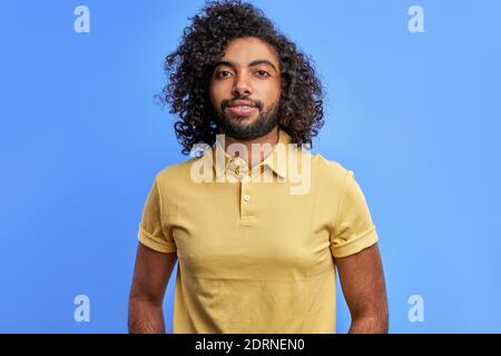 ragazzo arabo che si pone con sicurezza guardando la macchina fotografica, giovane uomo con la pelle scura in studio su sfondo blu Foto Stock