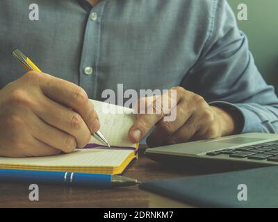 Un uomo effettua i calcoli nel notebook. Finanza domestica, prestiti e tasse. Foto Stock