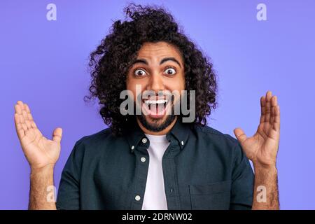 il giovane arabo è sorpreso da qualcosa, reagisce emozionalmente sul someting, sulle notizie. l'uomo guarda la macchina fotografica con la bocca aperta e gli occhi grandi, felice. Foto Stock