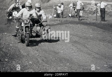 Anni '1970, storico, Motorcross....fuori sul circuito sterrato, piloti maschili su una moto e sidecar che gareggiano in un evento di corsa, Inghilterra, Regno Unito. Foto Stock