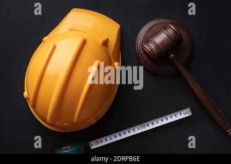 Gavel giudice in legno, casco giallo da costruzione e nastro. Concetto giuridico relativo al lavoro. Vista dall'alto. Foto Stock