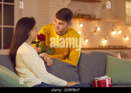 Sorridendo ragazzo ragazzo o marito dando fiori al suo Donna fidanzata o moglie per San Valentino Foto Stock
