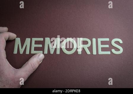 Dita umane che tengono le memorie di parola scritte con lettere di plastica su sfondo di carta marrone, concetto Foto Stock
