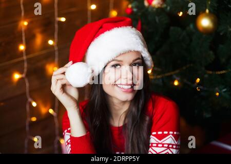 Giovane ragazza sorridente vestita in cappello di Santa sullo sfondo di Natale Foto Stock