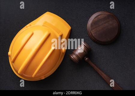 Casco da costruzione e giudici gavel su sfondo nero. Vista dall'alto. Concetto di legge sulla costruzione. Foto Stock