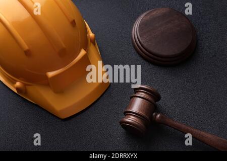 Casco da costruzione e giudici gavel su sfondo nero. Vista dall'alto. Legge sulla costruzione Foto Stock