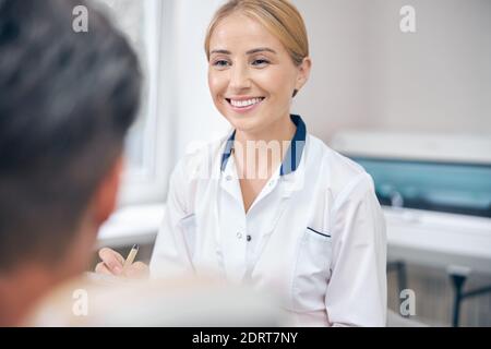 Allegro dentista femminile durante l'appuntamento con l'uomo in clinica Foto Stock