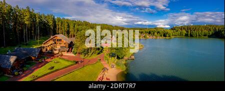 Un'immagine aerea di un bellissimo lago circondato dal verde foresta e piccole case di legno Foto Stock