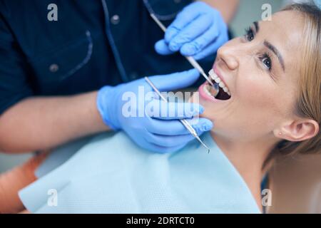 Jolly giovane donna che viene esaminata dal dentista Foto Stock