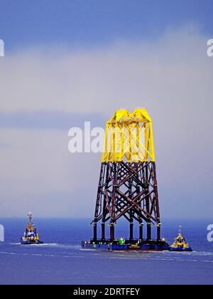 Turbine eoliche in cima alla chiatta Wismar con rimorchiatore Multratug 18 Passando dal molo di Tynemouth sotto la pioggia per il campo di Nigg In Scozia e fabbricato a Smulders H. Foto Stock