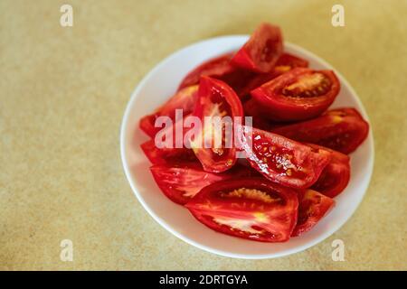 Pomodori appena macinati su un piatto bianco. Piatto bianco con fette di pomodori su un tavolo. Ampio spazio per la copia. Foto Stock