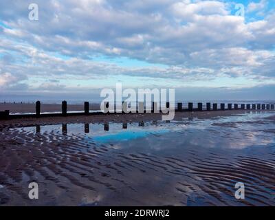 Vista invernale della spiaggia di Bridlington, una popolare località balneare nell'East Riding dello Yorkshire Inghilterra UK con il cielo riflesso nell'acqua di mare. Foto Stock