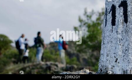 Una squadra di escursionisti che chiacchiera all'arrivo in cima un sentiero escursionistico - proprio accanto a un cemento fatto palo con il numero 111 su di esso Foto Stock