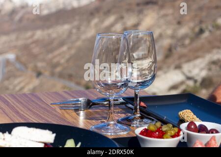 Insalata greca (choriatiki) e foglie d'uva, su un tavolo servito con cucina greca e mediterranea, nel villaggio di Oia, isola di Santorini, Grecia, Europa. Foto Stock