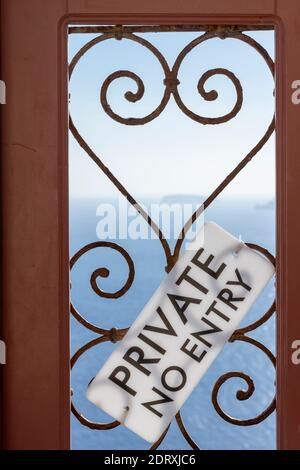 Cartello "privato - senza ingresso" su una porta di legno con barre a forma di cuore, che informa i visitatori che l'ingresso è consentito solo a discrezione del proprietario. Foto Stock