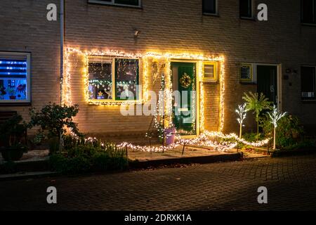 Vista notturna di molte luci sulla parte anteriore di una casa in una città olandese. Decorazione di Natale. Foto Stock