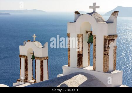 Belfries di una chiesa greco-ortodossa che guarda il blu profondo del Mar Egeo, nel villaggio di Oia, isola di Santorini, Mar Egeo, Grecia, Europa Foto Stock