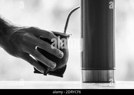 Immagine in scala di grigi selettiva di un accoppiamento di calabash con mano tazza con paglia Foto Stock