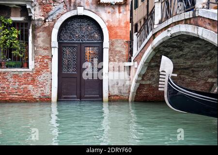 Canale di Venezia con gondola e porta di casa Foto Stock