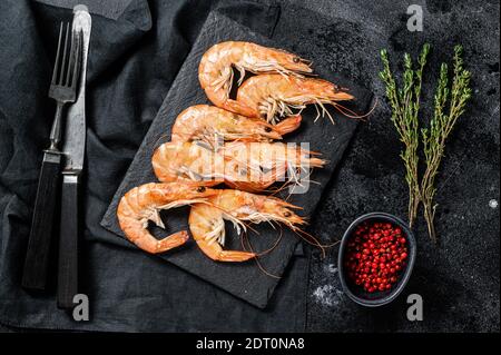 Gamberi freschi crudi, gamberi Langostino su una tavola di pietra. Sfondo nero. Vista dall'alto. Foto Stock