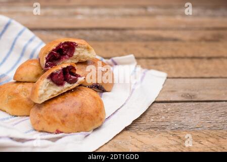 Pies pirozhki (patties) al forno tradizionale russo o ucraino su un tovagliolo su sfondo di legno Foto Stock