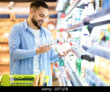 Man esegue la scansione del codice sui prodotti utilizzando lo smartphone Foto Stock