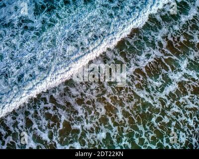 Vista aerea di un surfista che entra in acqua con la sua tavola da surf su una spiaggia nelle Asturie, Spagna. Foto Stock