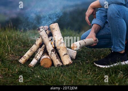 uomo viaggiatore sul campeggio in montagna all'aperto. impostazione del fuoco campeggio Foto Stock
