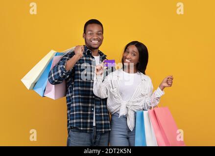 Sorridente giovane alunni afro-americani si accoppia con molti negozi colorati i sacchetti mostrano la carta di credito Foto Stock