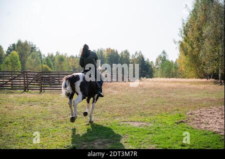 Passeggiata a cavallo di una giovane ragazza in luoghi con splendidi paesaggi di campagna autunnali. Foto Stock