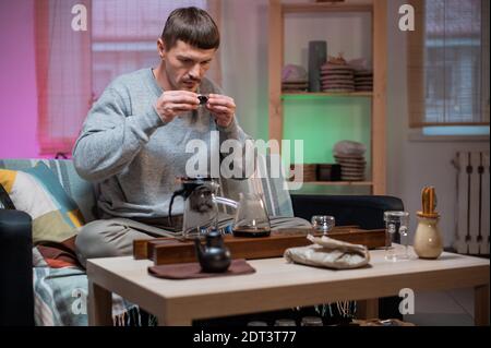 Un uomo prova il tè, che ha estratto per sé da un pezzo di torta cruda del tè secondo una ricetta orientale Foto Stock