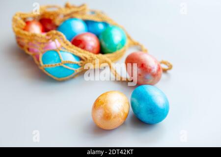 Diverse uova multicolore in una borsa a maglia Foto Stock