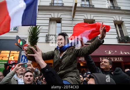 I fan del fumetto francese Dieudonne M'Bala M'Bala si riuniscono vicino ad un teatro a Parigi, uno di loro ondeggia la bandiera nazionale francese e tiene un ananas il 11 gennaio 2014 a Parigi, Francia. Dieudonne è stato ripetutamente condannato per aver incitato l'odio razziale o l'antisemitismo e ha accettato di abbandonare uno spettacolo controverso che è stato vietato in diverse città. Dopo che uno spettacolo di Parigi è stato oggi vietato dalle autorità, ha detto a una conferenza stampa che non farà più lo spettacolo 'le Mur' e lo sostituirà invece con una nuova prestazione. Il fumetto è stato condannato lo scorso autunno per aver usato la parola 'Shoanana Foto Stock