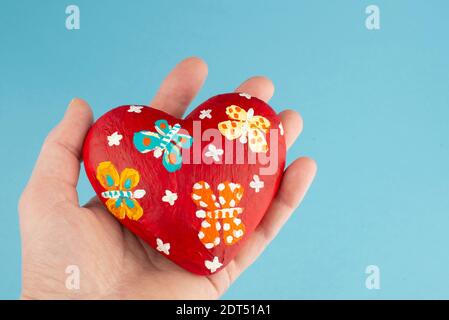 Mano donna che tiene il cuore rosso su sfondo blu. Concetto di San Valentino. Vista dall'alto. Primo piano. Copia spazio. Foto Stock