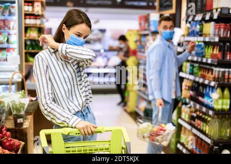 Malato giovane Donna tosse a gomito, Guy guardandola Foto Stock