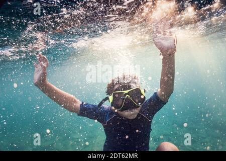 Ragazzo che indossa una maschera subacquea che nuota sott'acqua Foto Stock