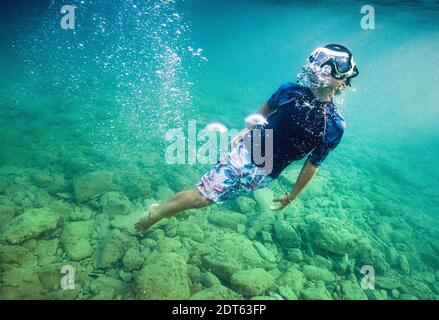 Ragazzo che indossa una maschera subacquea che nuota sott'acqua Foto Stock