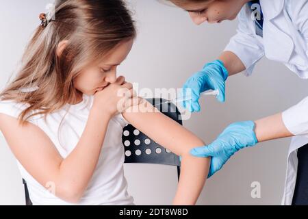 La ragazza viene vaccinata da un medico in un cappotto bianco. Vaccinazione. Lotta contro le malattie.COVID 19. Il concetto di assistenza sanitaria durante un'epidemia Foto Stock