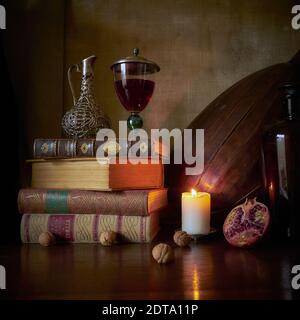 Una classica vita still-life in stile dipinto olandese vecchi maestri con luce a candela, melograno, caraffa d'argento. Libri antichi, bicchiere di vino e liuto di chitarra Foto Stock