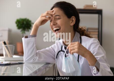 Felice dottoressa ride seduta alla scrivania in clinica Foto Stock