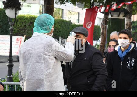 Tunisi, Tunisia. 21 Dic 2020. Un lavoratore medico controlla la temperatura per i cittadini in attesa di test gratuito COVID-19 nel centro di Tunisi, Tunisia, 21 dicembre 2020. Il Governo Municipale di Tunisi ha effettuato prove libere e rapide di COVID-19 in tre zone densamente popolate della città da lunedì a mercoledì. Credit: Adel Ezzine/Xinhua/Alamy Live News Foto Stock