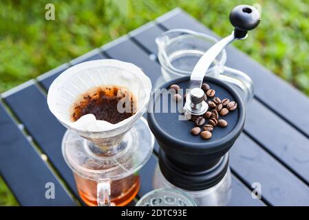 fai gocciolare il barista del caffè versando l'acqua sulla birra filtrata, fai gocciolare il caffè a mano in un recipiente di vetro all'aperto Foto Stock