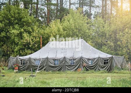 Grande campo militare tenda con finestre e una stufa su il prato nella foresta Foto Stock