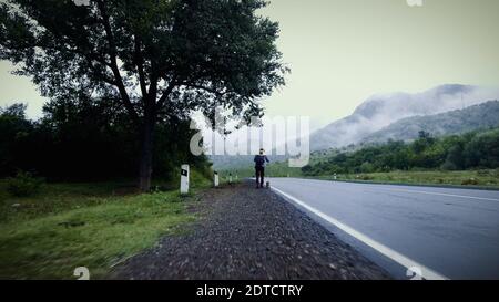Dog Walk con proprietario. Un ragazzo cammina al mattino con il suo cane su una strada bagnata in natura foto, immagine, fermo. Passeggiata con il cane con il proprietario il giorno di Foggy. Foto Stock