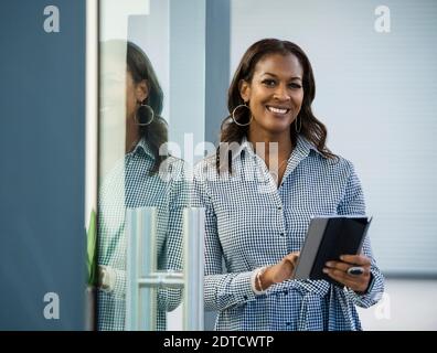 Ritratto di sorridere imprenditrice con tavoletta digitale in ufficio Foto Stock