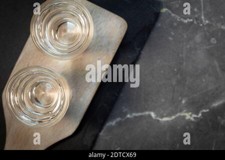 Due bicchieri con vodka su tavola di legno. Sullo sfondo di pietra grigia Foto Stock