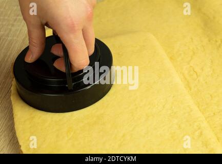Una donna taglia gli sbozzi dall'impasto laminato. Per la preparazione di pan di zenzero, puffs e succosa. Cottura fatta in casa Foto Stock